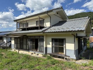 日本瓦屋根の白い建物で、2階屋根にはベランダがある木造2階建ての建物の外観写真