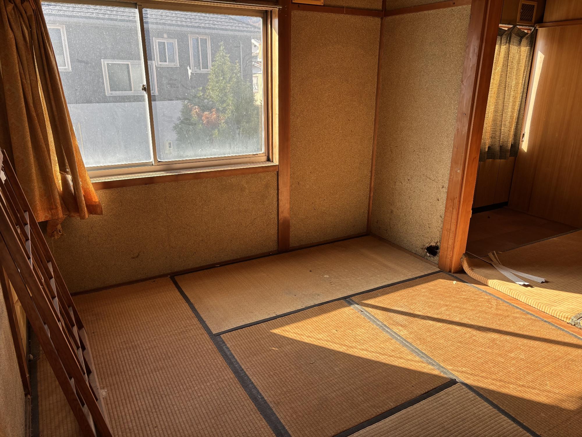 左側奥にアルミガラスサッシ戸、その左側に閉じたカーテン、右側奥に隣部屋の閉じたカーテンがある2階4.5帖和室内観の写真