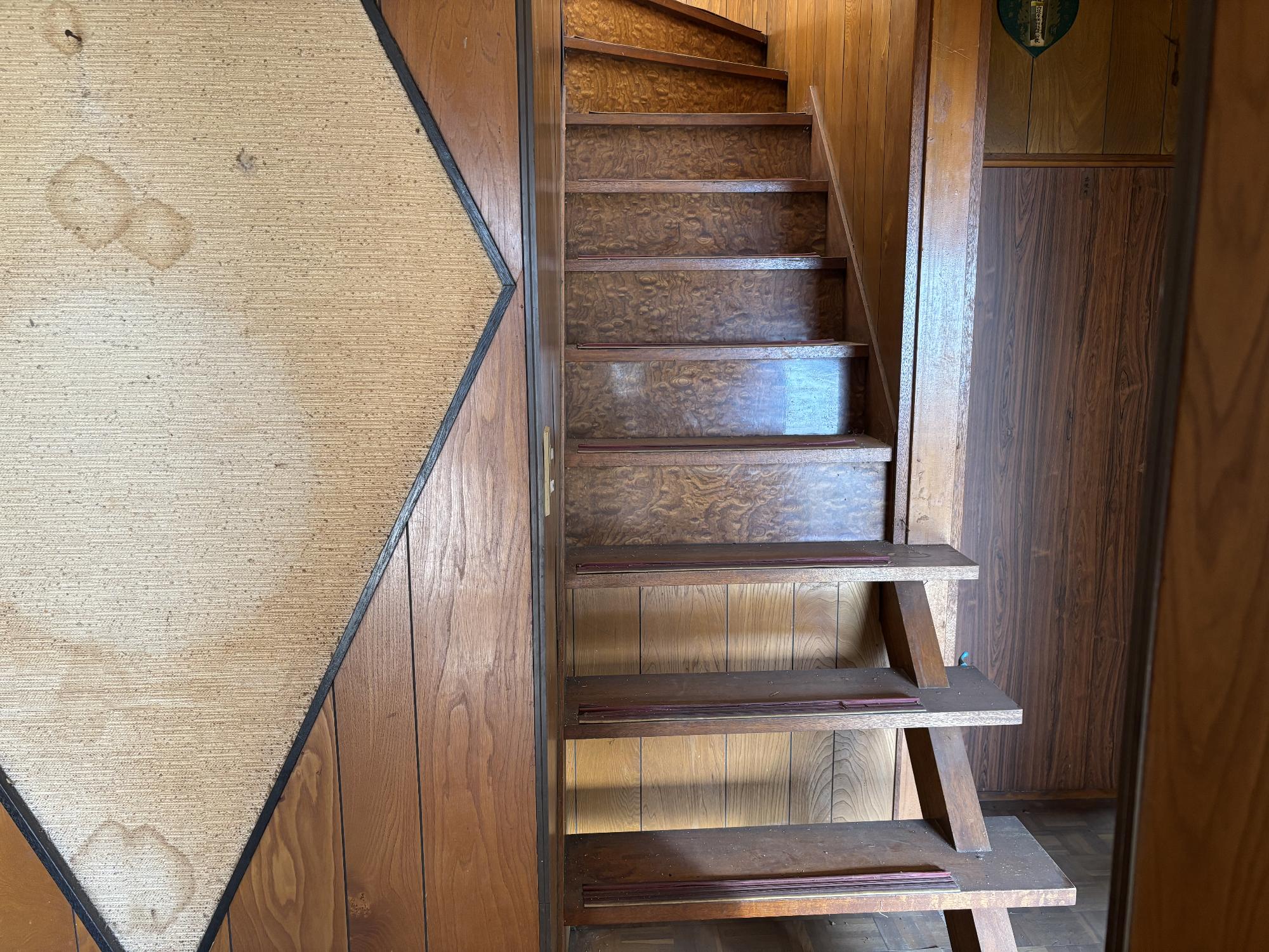 右側に板壁、正面中央に螺旋階段がある階段の写真