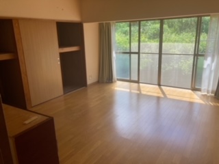 右側奥にサッシ、その左右にカーテン、左側奥に押入れがある洋室内観写真