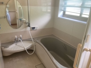 左側奥に鏡、その手前にシャワー、右側奥に曇りガラス、中央真ん中に浴槽がある浴室の写真