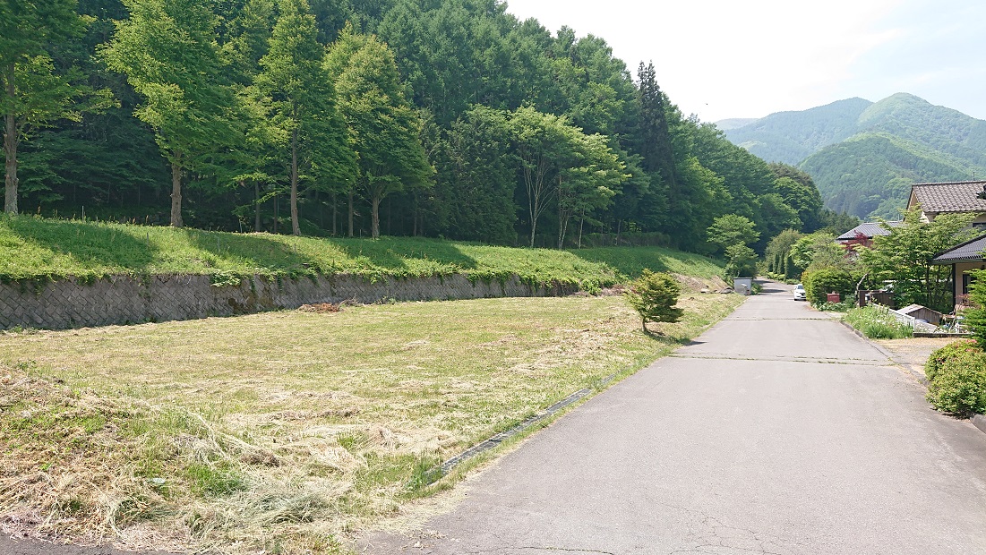 生茂る木々の下の芝の分譲地を撮影した写真